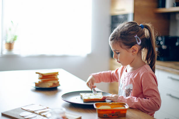 istock Happy girl making sandwiches in the kitchen 2188485976
