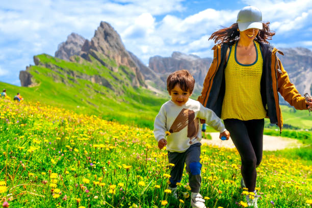 istock Mother and son running through wildflower meadow in seceda, dolomites 2188489034