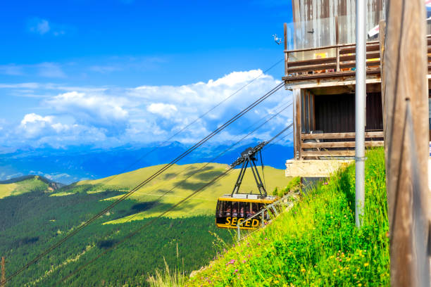 Cable car transporting tourists up seceda mountain with stunning views of the dolomites in summer