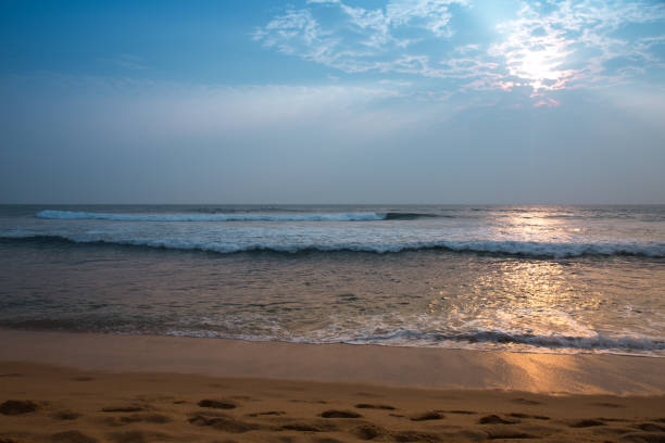 The ocean is calm and the sky is blue. The sun is shining on the water, creating a beautiful reflection