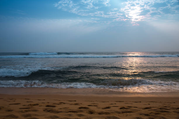 The ocean is calm and the sky is blue. The sun is shining on the water, creating a beautiful reflection