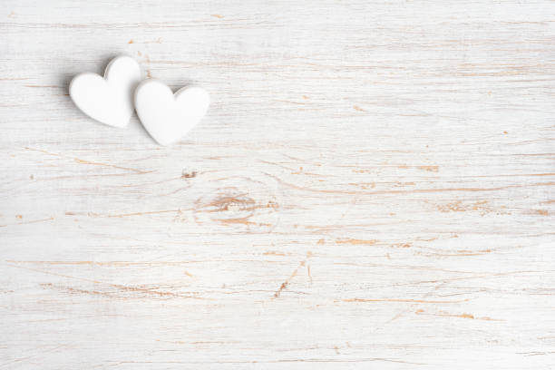 istock Two white hearts mock up on bleached wooden background with space 2188490285