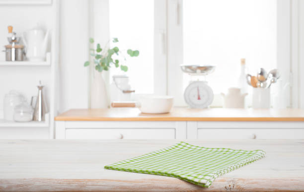 istock Green checkered napkin on bleached wooden table with blur kitchen window interior background 2188490291