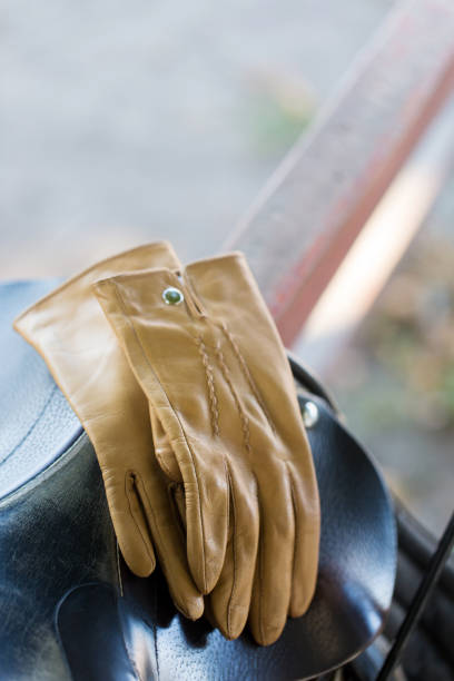 Beige leather gloves on a saddle for a horse, close-up
