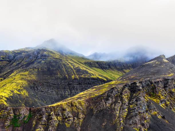 A stunning view of moss-covered volcanic mountains under a cloudy sky in Iceland.