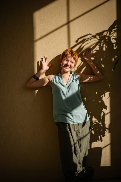 istock Smiling woman posing against a sunlit wall 2188498509