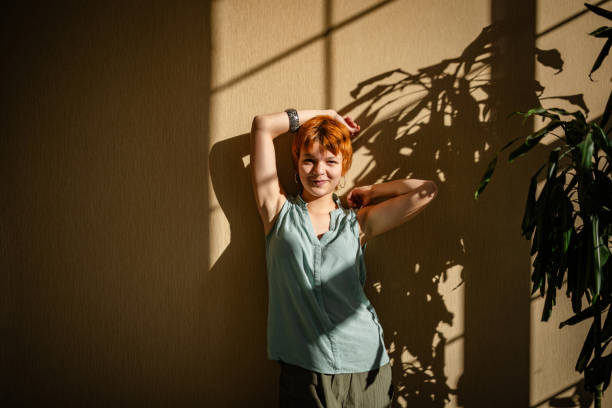istock Woman cheerfully posing by wall under shadowed sunlight. 2188498967