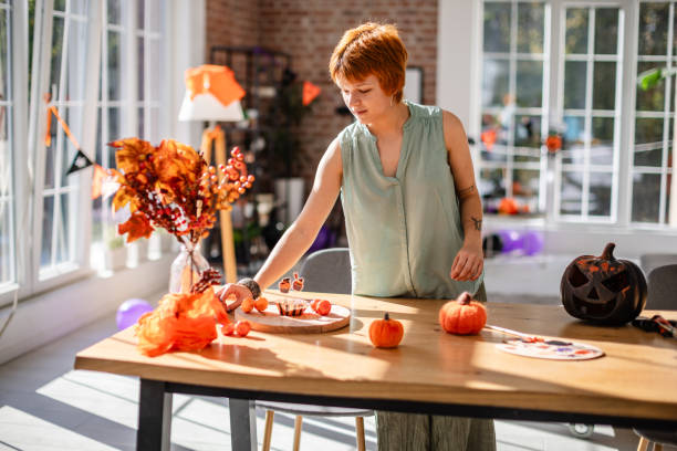 istock Woman decorating for Halloween in sunlit room 2188499076