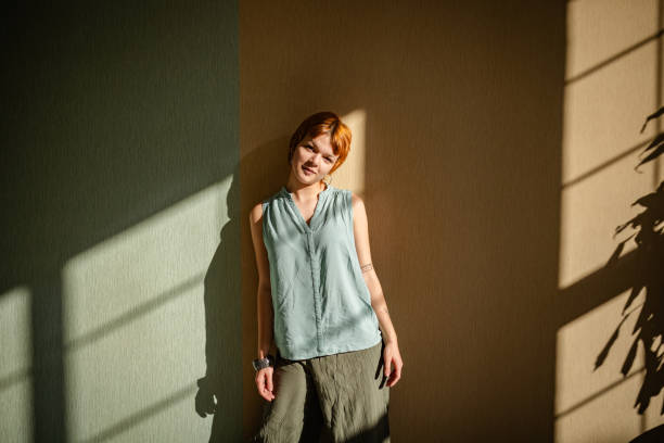 istock Woman leaning against wall in artistic shadow light. 2188499757