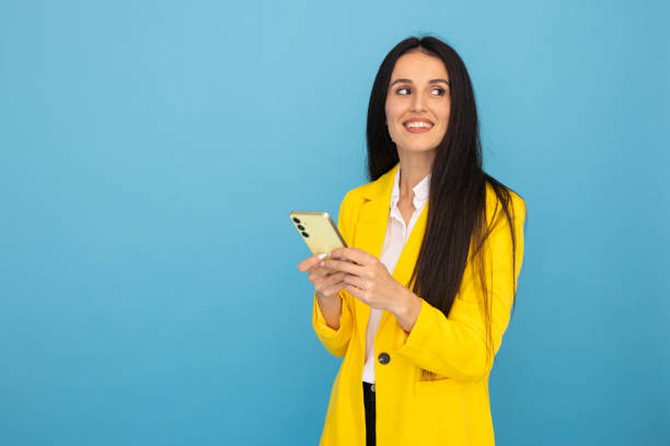 istock Young businesswoman in a yellow blazer using a smartphone 2188499809