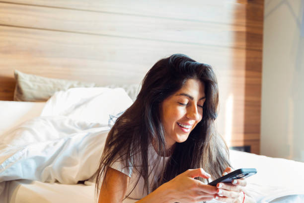 istock Beautiful young  smiling woman  using mobile phone in bed 2188499857