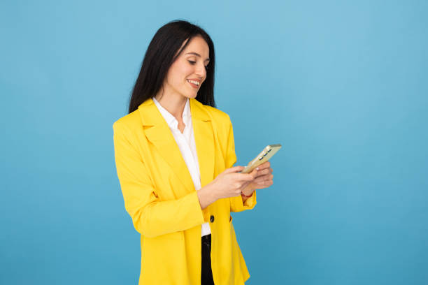 istock Professional woman in a yellow blazer checking her phone 2188499983
