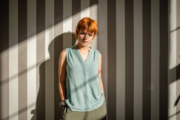 istock Woman stands in shadow-striped light wearing green top 2188501457