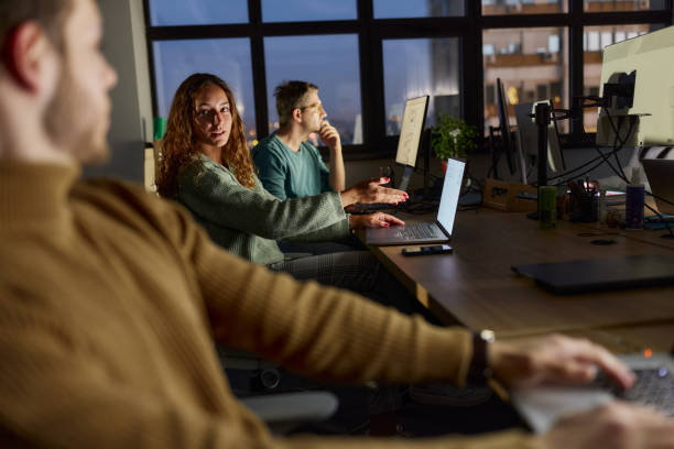 istock Female programmer working on laptop and talking to her colleague in the office. 2188505364