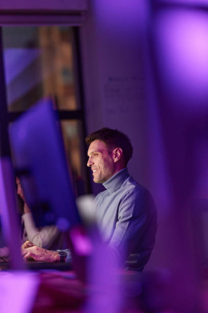 Happy male programmer working on a computer late in the office.