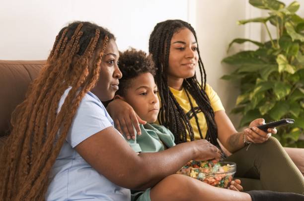 istock Happy family having popcorns while watching TV as they sit on sofa 2188507081