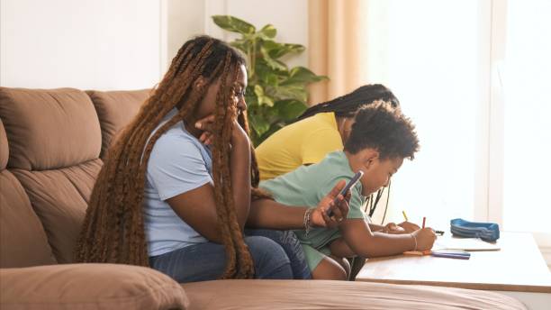 istock Mother using smartphone while daughter and son coloring in book at home 2188507390