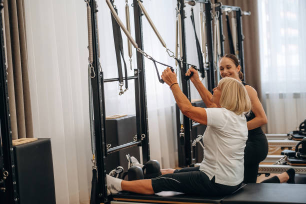 istock Using training equipment. Female trainer is helping old woman to exercise 2188511307