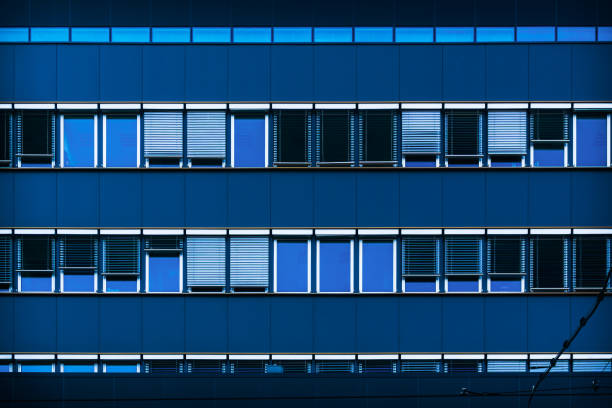Modern Glass Building with Reflective Windows and Blue Accent Panels in Urban Setting