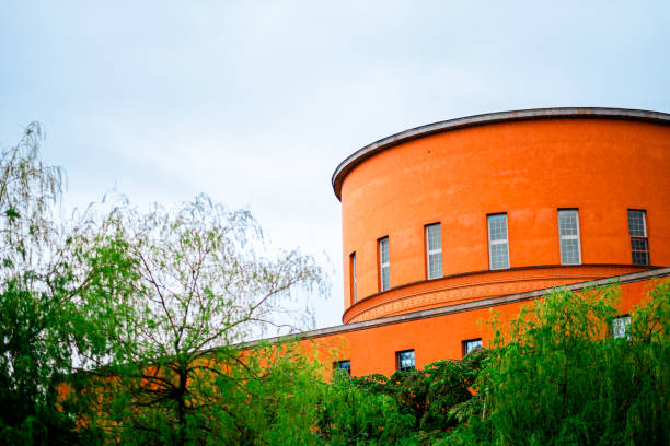 istock Bright Orange Building with Circular Architecture And Green Foliage Under A Blue Sky Creates A Vibrant Contrast In Urban Landscape 2188513644