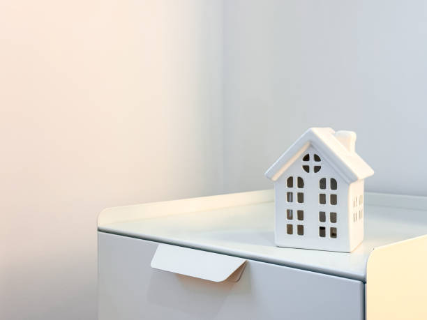 istock Minimalist white ceramic house on modern nightstand in bright interior space 2188516286