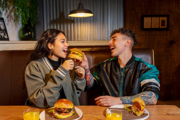 istock Happy couple sharing a burger at restaurant table to eat 2188517713