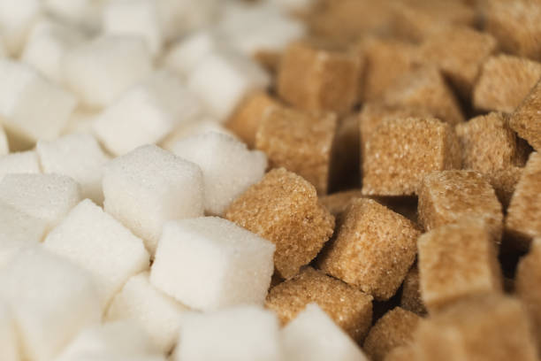 istock Cubes of unrefined brown demerara sugar and white refined beet sugar. 2188520672