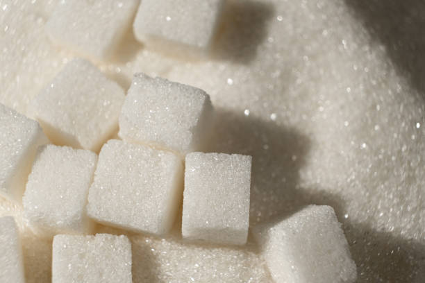 Common sugar glass bowl and three sugar cubes isolated on a white background.