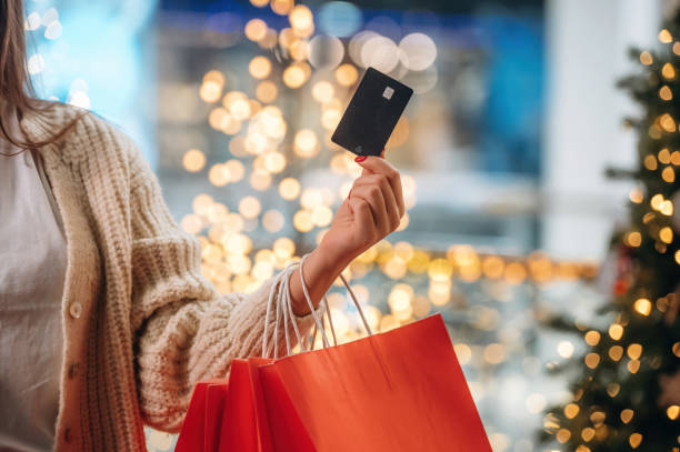 Ready for payment, holding credit card. New year shopping and presents. Woman is near the Christmas tree stock photo