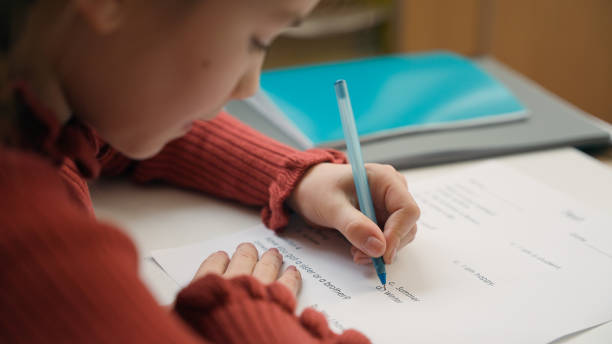istock Caucasian clever happy little girl school test study task exam writing notes class lesson learn write copybook kid schoolgirl child pupil studying learning primary education smiling at camera at desk 2188521366