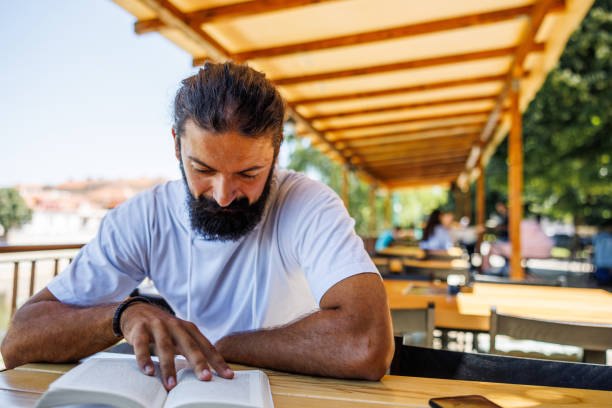 Jewish Bearded man reading the old testament in a red book  of tanach. The man is showing happiness in heading