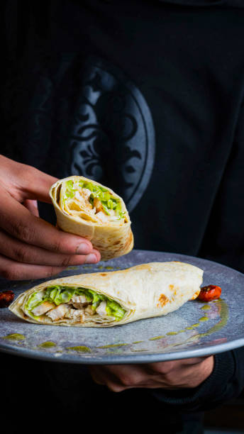 istock Hand holding a delicious chicken wrap on a plate with fresh vegetables 2188530836