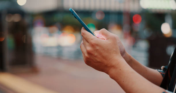 City, hands and scroll with smartphone outdoor with night, playing game and browsing social media online. Japanese person, phone or internet search for travel schedule, web information or chat space