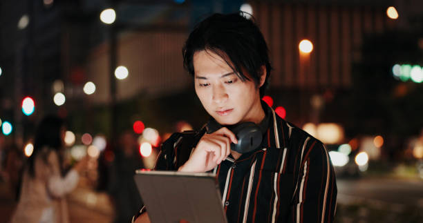 istock Creative, serious and man with tablet, night and video editor with ideas, headphones and project. Content creation, contemplating and Asian person with tech, post production and process in Japan 2188533581