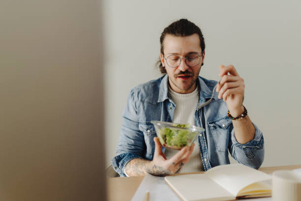 istock Young man working at home office and eating salad 2188533611