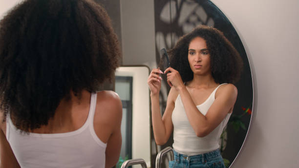 istock African American woman with curls suffer with haircare problem looking at mirror reflection young upset girl female suffering from dry hair trying to brush curly tangled hairdo hard beauty trouble 2188533730