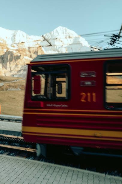 Red train passing by snowy mountain in switzerland, transportation concept
