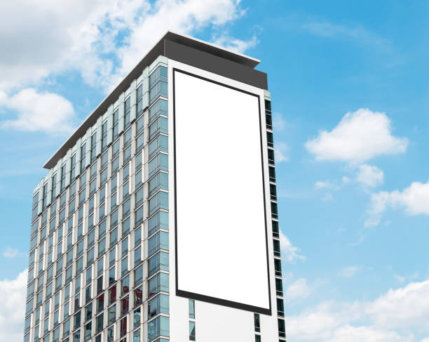 Mock up white vertical large LED display billboard on tower building with blue sky background .Clipping path for mockup