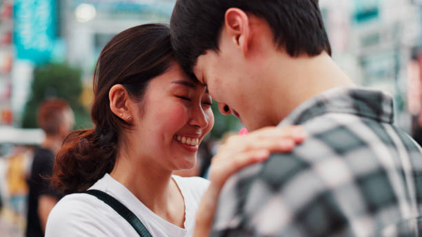 istock Love, happy couple and forehead touch outdoor for support, loyalty and commitment on vacation. Japanese man, woman and embrace for romantic relationship, connection and trust partner on date in city 2188540155