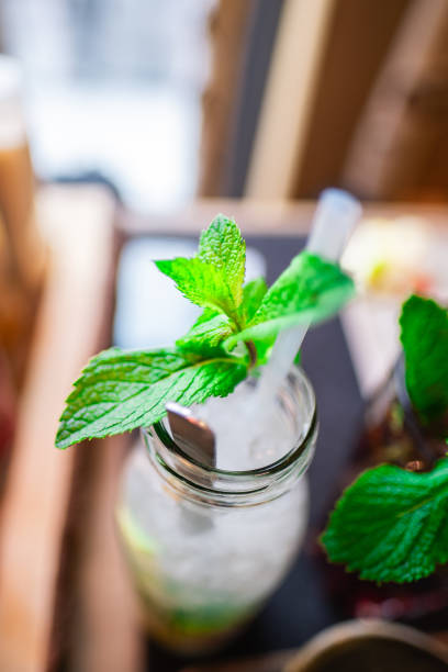 A refreshing summer drink with fresh mint leaves in a glass jar at a cozy cafe. The image showcases a vibrant and inviting setting, perfect for spring and summer enjoyment.