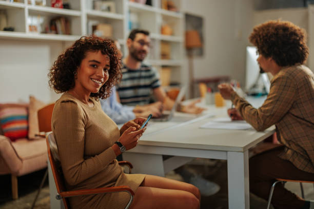 istock Young woman using phone during a meeting with colleagues in the office 2188540346