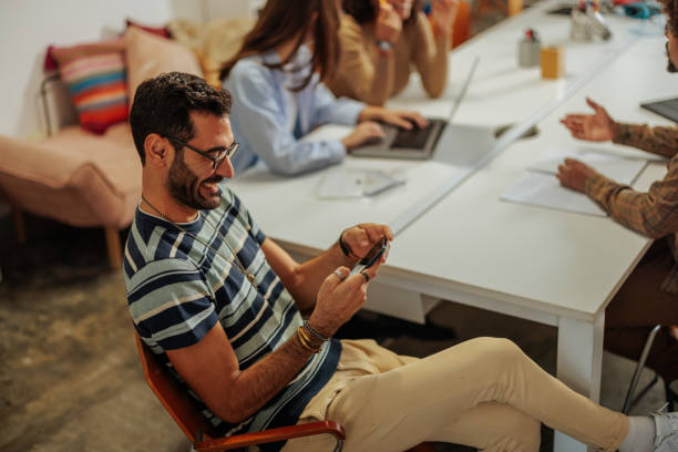 istock Young man using smartphone during business meeting in modern office 2188540355