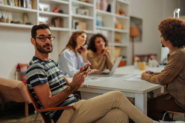 istock Young man using smartphone during office meeting with colleagues 2188540365