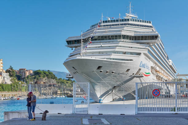 Savona, Italy - December 06, 2024: The large Costa Pacifica cruise ship is docked in Savona harbor, its impressive size and multiple decks set against a clear blue sky and mountainous backdrop.