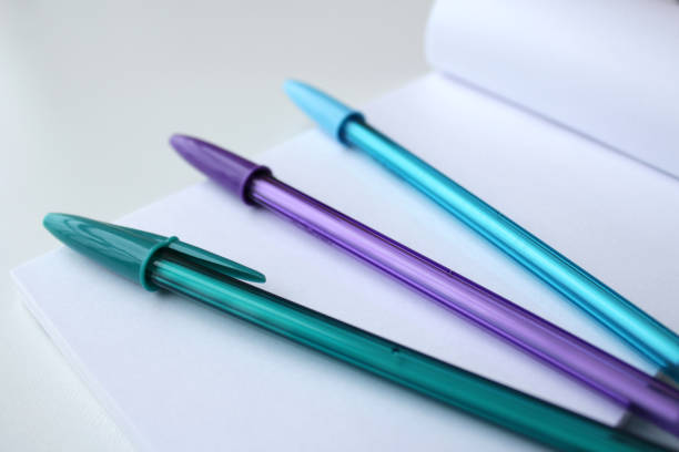 Three cool color pens on top of a blank paper notepad page.