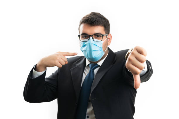 istock Male entrepreneur pointing at mask making thumb-down gesture 2188549649