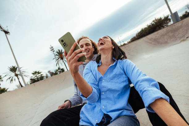 Young couple laughing while taking a selfie in a skatepark