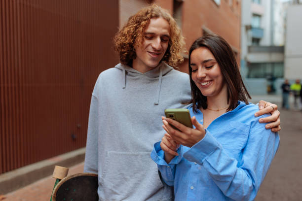 istock Young couple using smartphone and holding skateboard in urban setting 2188551402