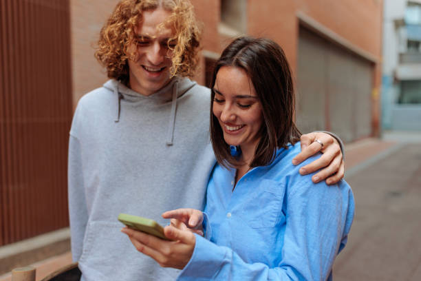 istock Young couple smiling and using a smartphone in the city 2188551410