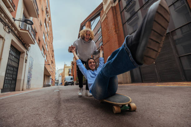 istock Young man pulling woman on skateboard in city street 2188551418